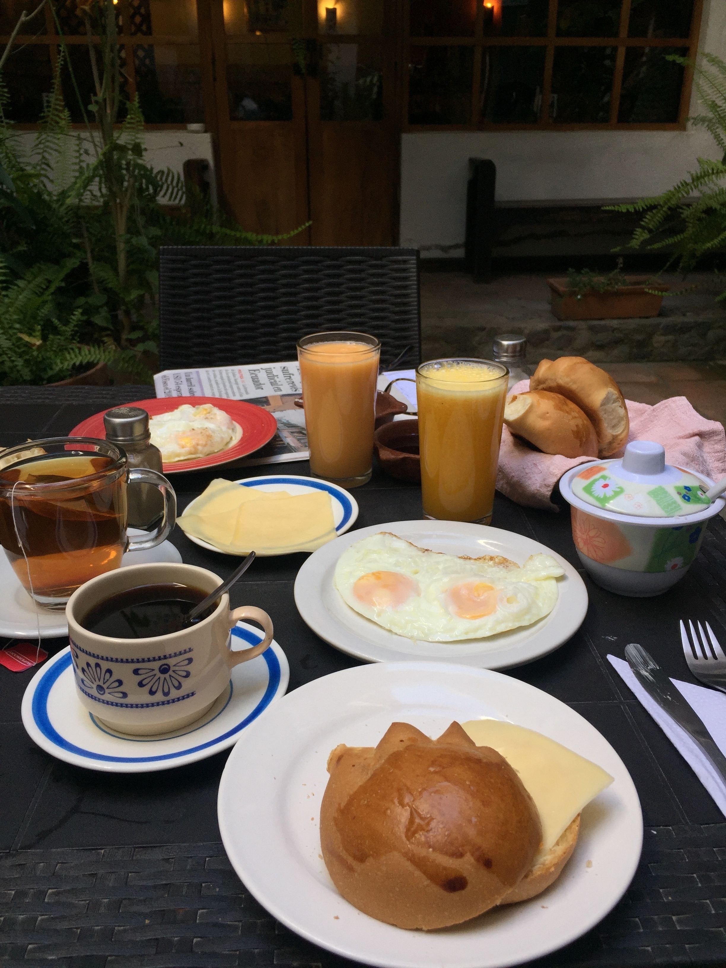 Una mesa de desayuno con diversos alimentos, como huevos, tostadas y jugo.