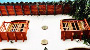 A building with two balconies, a tiled roof, and a wall-mounted light fixture. - Hotel Doña Esther (Otavalo)