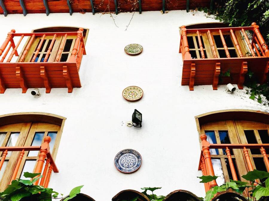 A building with two balconies, a tiled roof, and a wall-mounted light fixture.