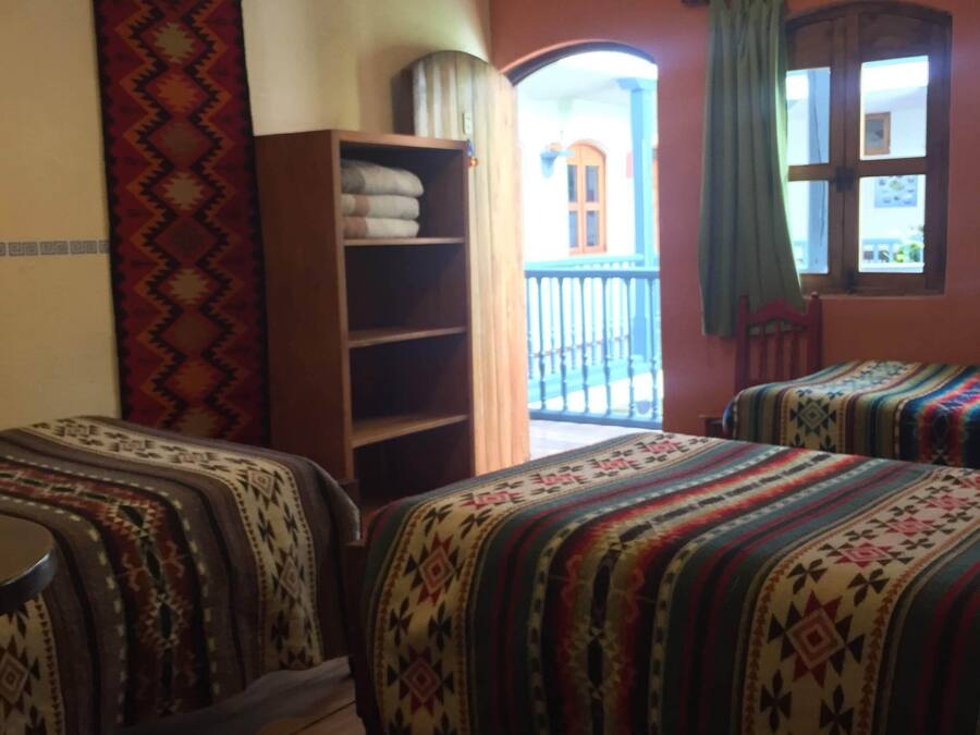Una stanza con due letti, un'armadio in legno, un pannello decorativo a parete e vista verso il balcone esterno.