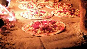 Pizzas assando em forno de tijolos.