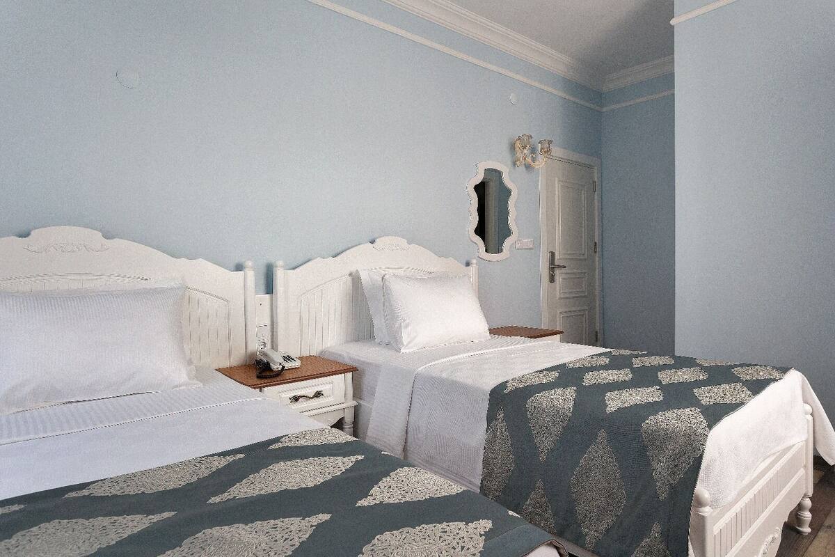 Un dormitorio con dos camas, una mesita de noche, un espejo y una puerta.