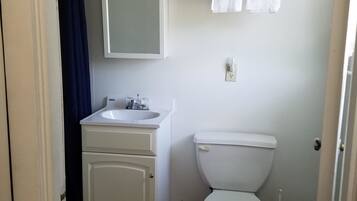 A bathroom with a white sink, mirror, and toilet. There is a towel rack with towels above the toilet.