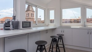 Una cocina moderna con armarios blancos, un ventanal y vistas a un edificio histórico.