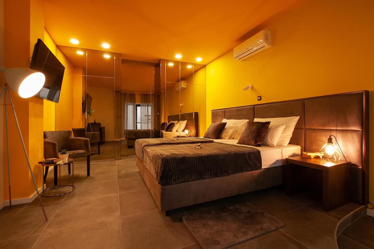 Quarto moderno com uma cama grande, escrivaninha, cadeira e televisão.