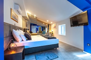 A modern bedroom with a large bed, bedside tables, a TV, and a mirror.
