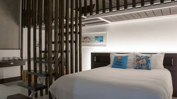 A modern bedroom with a large bed, a wooden partition, and a small desk with a chair.