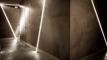 Un pasillo con paredes de concreto y una puerta al final.