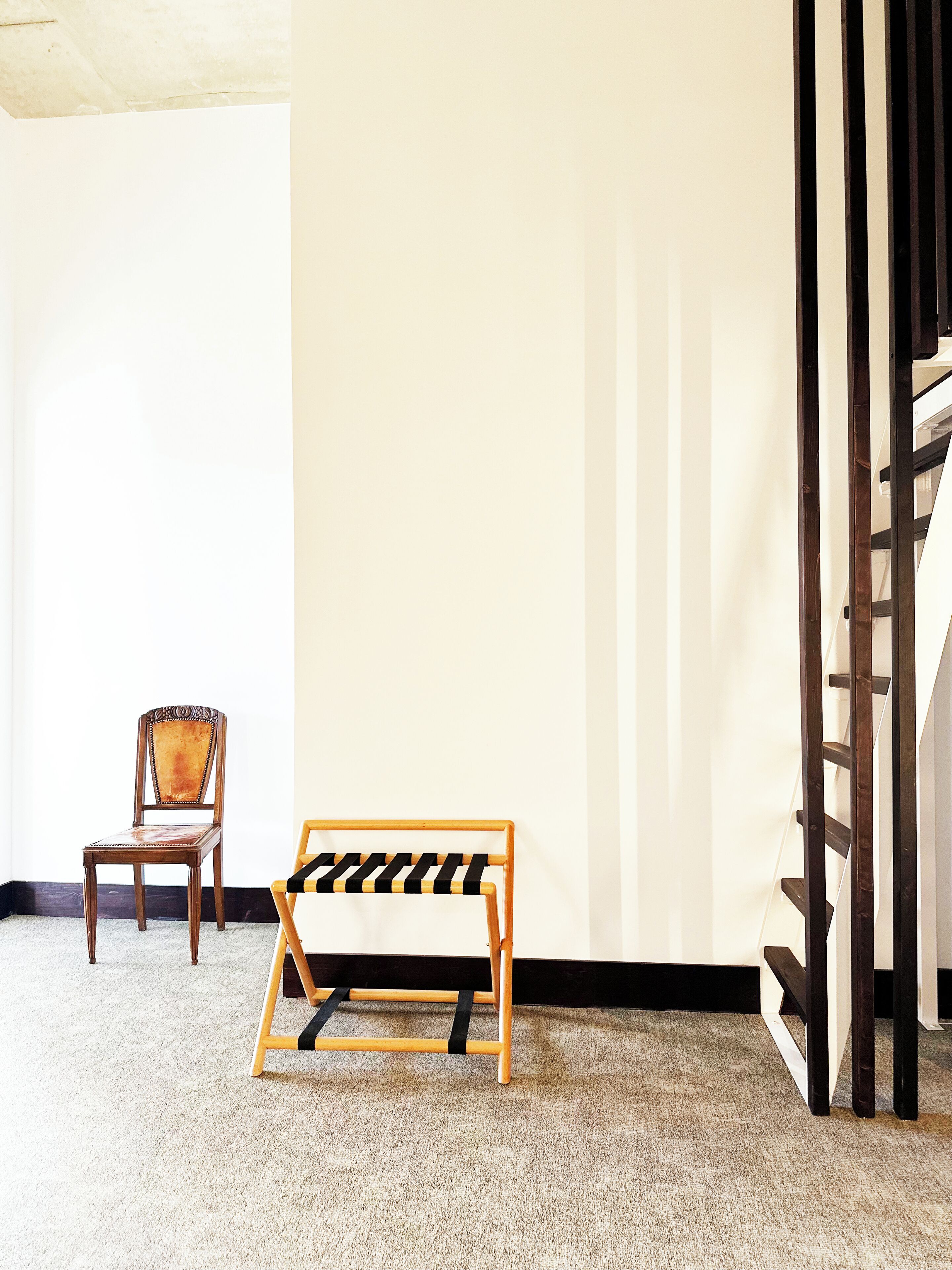 A room with a wooden chair, a bench, and a staircase.