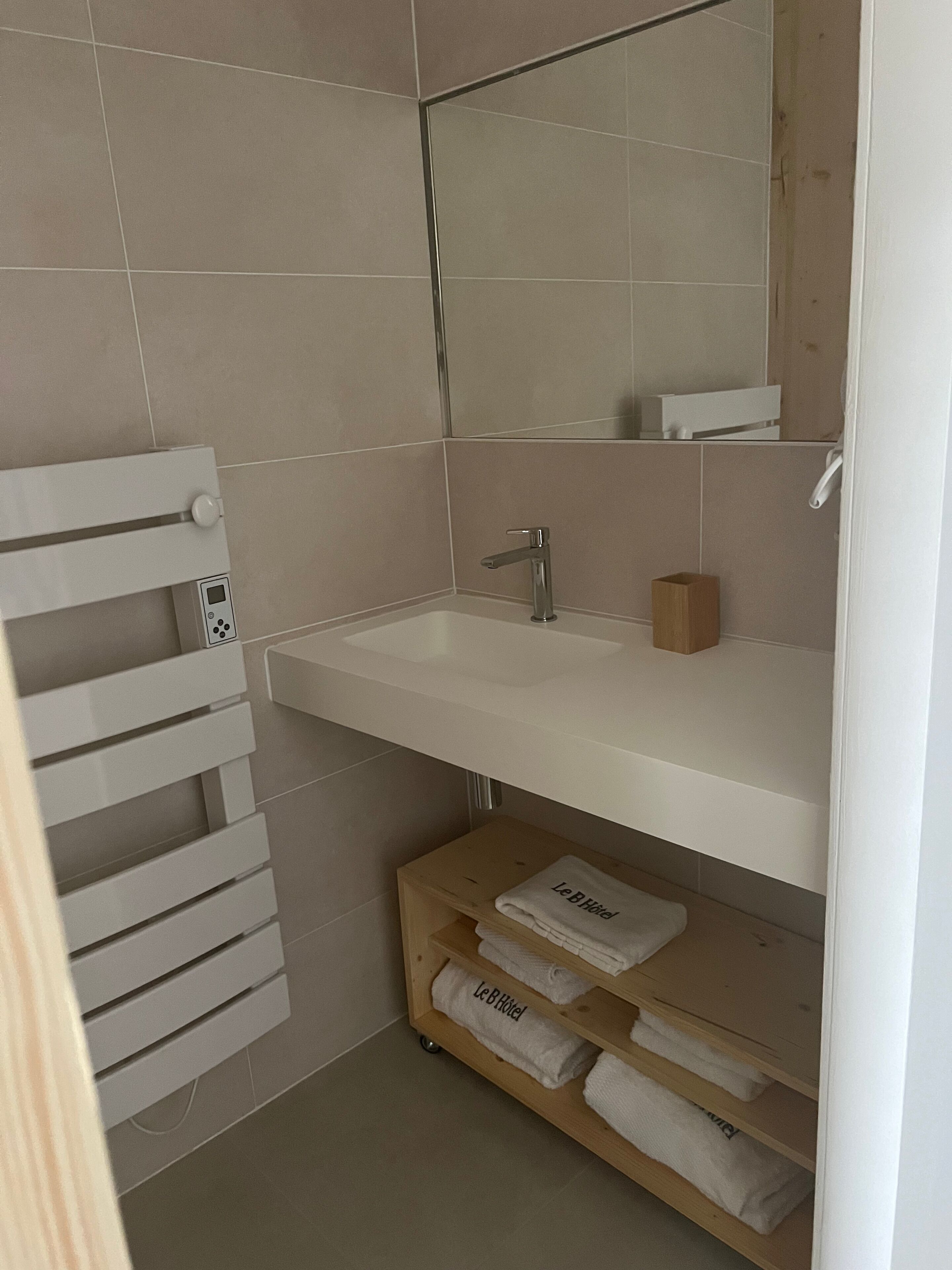 Ein Badezimmer mit einem weißen Waschbecken, einem Spiegel und einem Handtuchhalter.