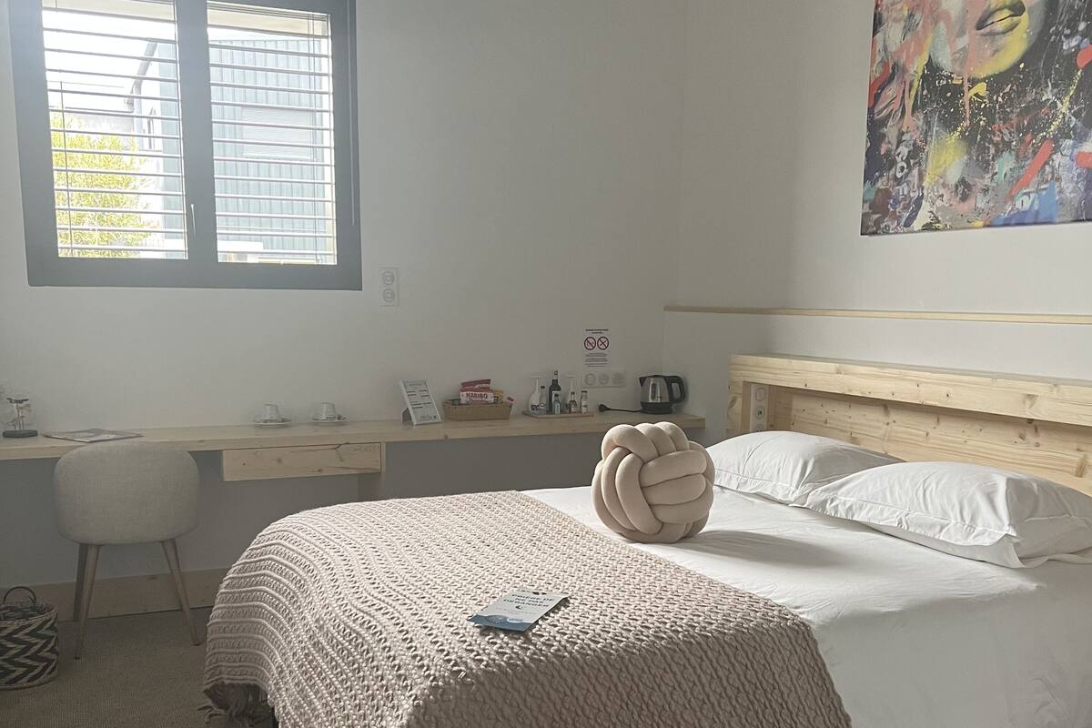 A bedroom with a bed, a desk, and a window.