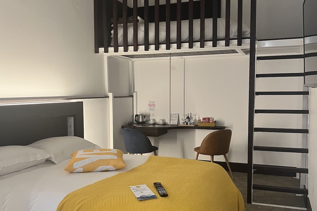 A modern hotel room with a bed, a desk, and a chair.