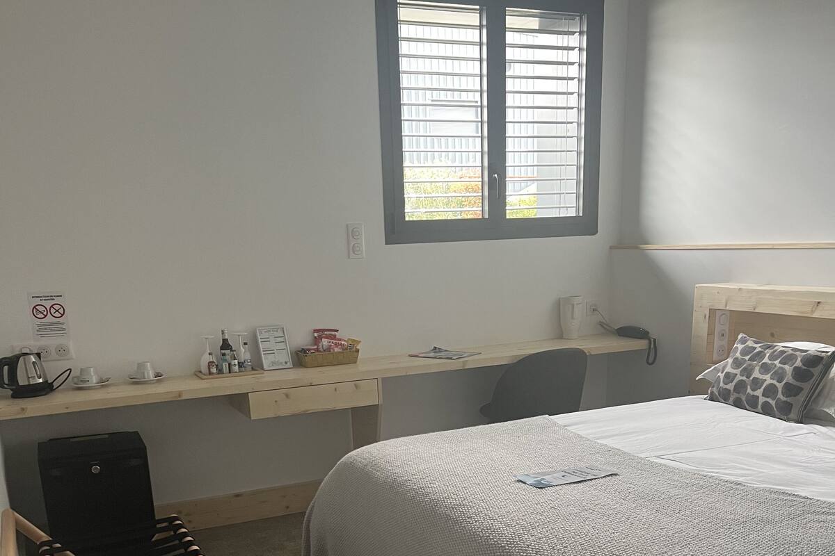 A bedroom with a bed, a desk, a chair, and a window.