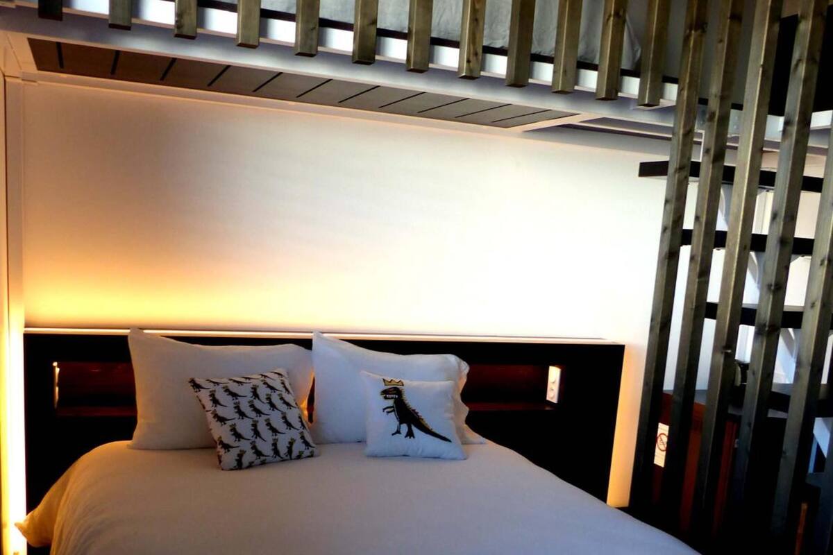 A hotel room with a bed, pillows, and a wooden slat headboard.