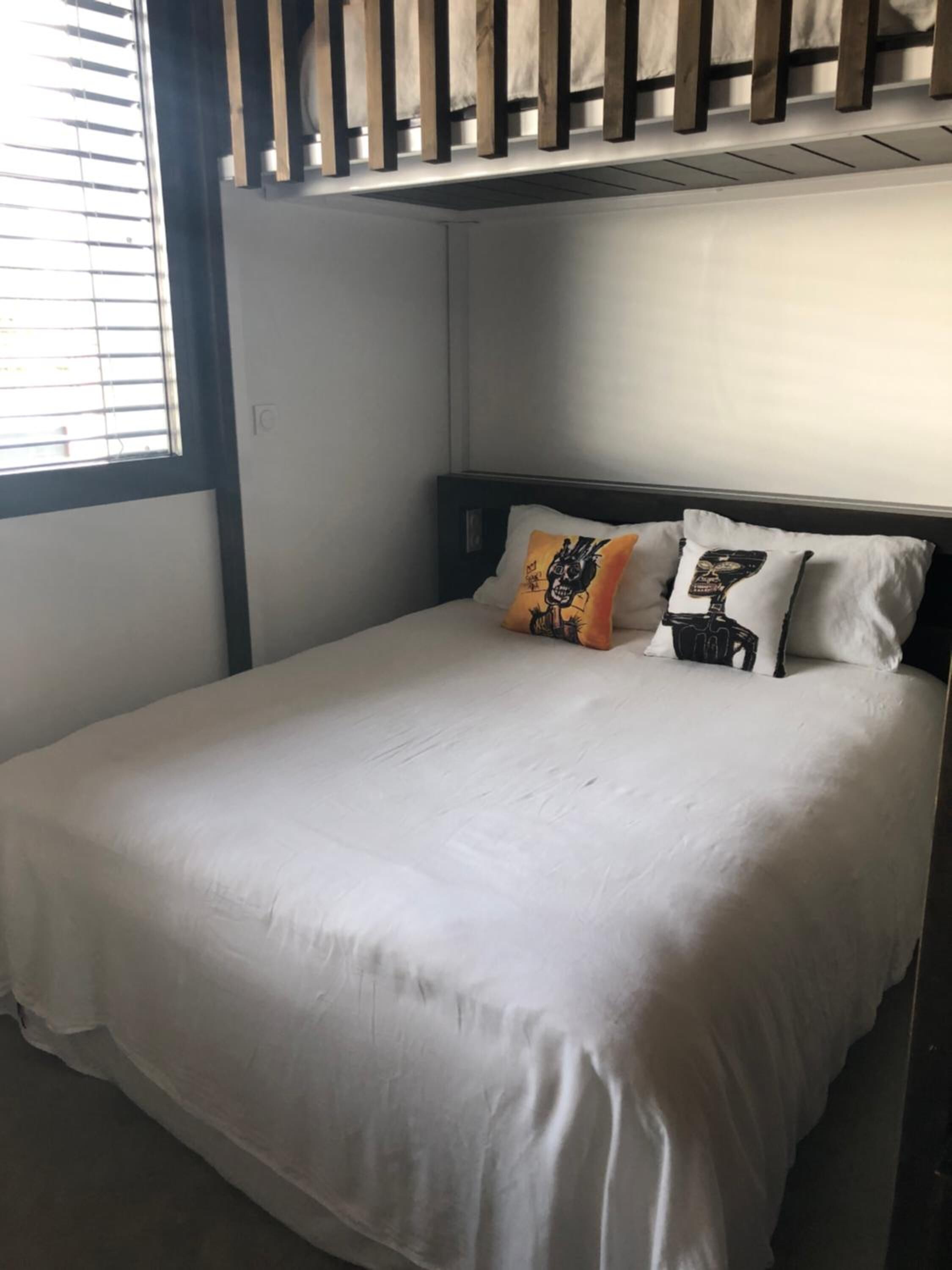 A bedroom with a bed, two pillows, a window, and a radiator.