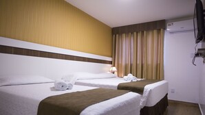 Ein Hotelzimmer mit zwei Betten, einem Fernseher, einer Klimaanlage und einem fenster mit Vorhängen.