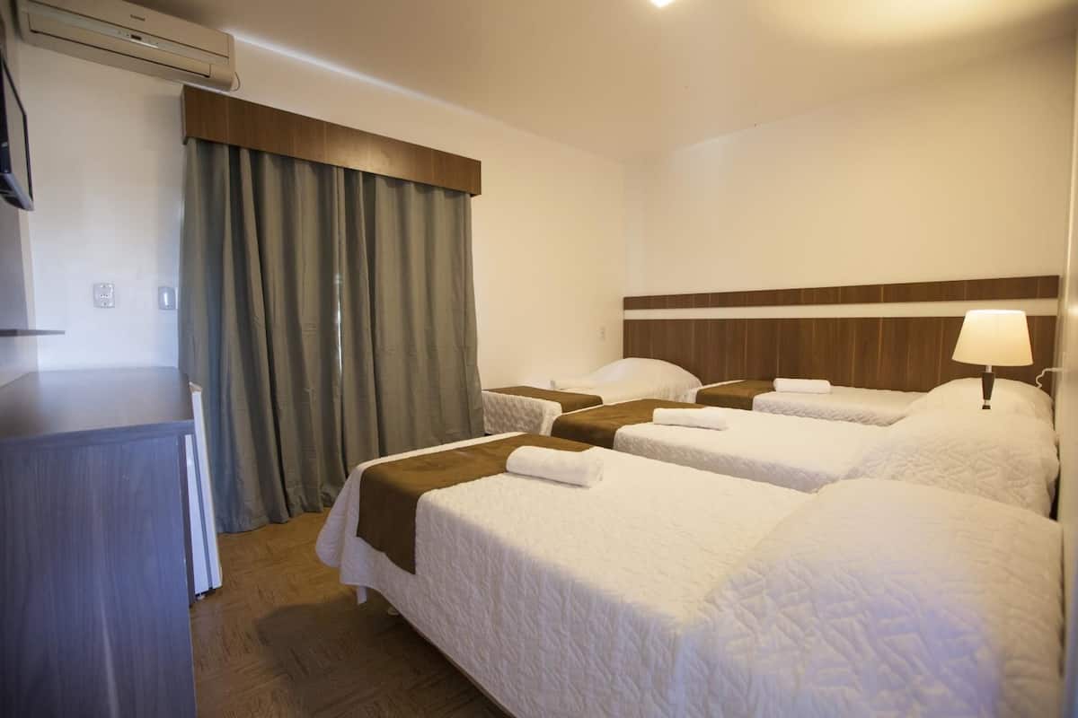 Habitación de hotel con cuatro camas, un escritorio y una lámpara.