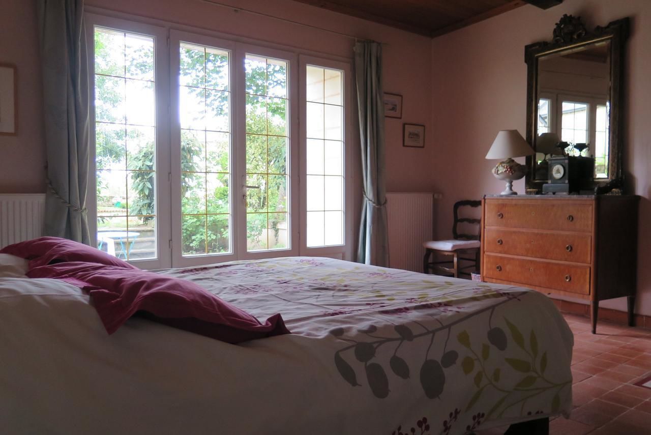 A bedroom with a bed, a dresser, a chair, and a window with curtains.