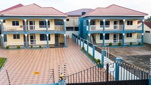 A multi-story building with balconies, a tiled courtyard, and a gated entrance. - Jacksonfields Apartments (Accra)