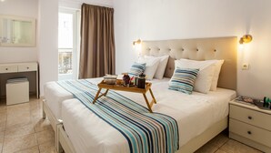 Habitación de hotel con una cama grande, una mesita de noche, un escritorio y una ventana con cortinas.
