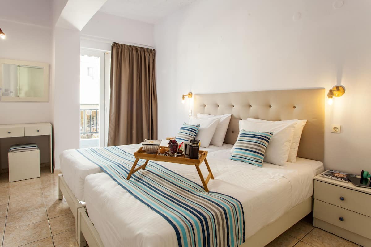 A hotel room with a large bed, a bedside table, a desk, and a window with curtains.