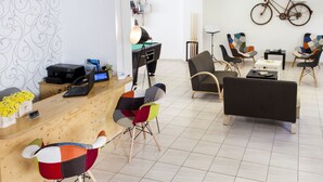Un moderno vestíbulo de hotel con un mostrador de recepción, sillas coloridas, un banco y una bicicleta colgada en la pared.