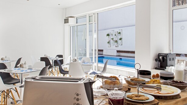 Un bufé de desayuno moderno con diversas opciones de comida y vista a la piscina.