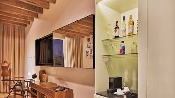 Una habitación moderna con techo de madera, un espejo grande, un aparador de vidrio con botellas y un escritorio de madera con sillas.
