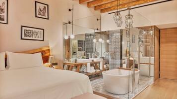 Quarto de hotel moderno com uma cama grande, chuveiro em cabine de vidro, banheira e teto de madeira.