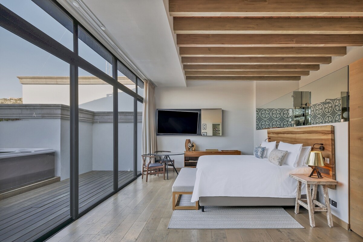 Ein modernes Schlafzimmer mit einem großen Bett, einem Fernseher und einem Balkon.