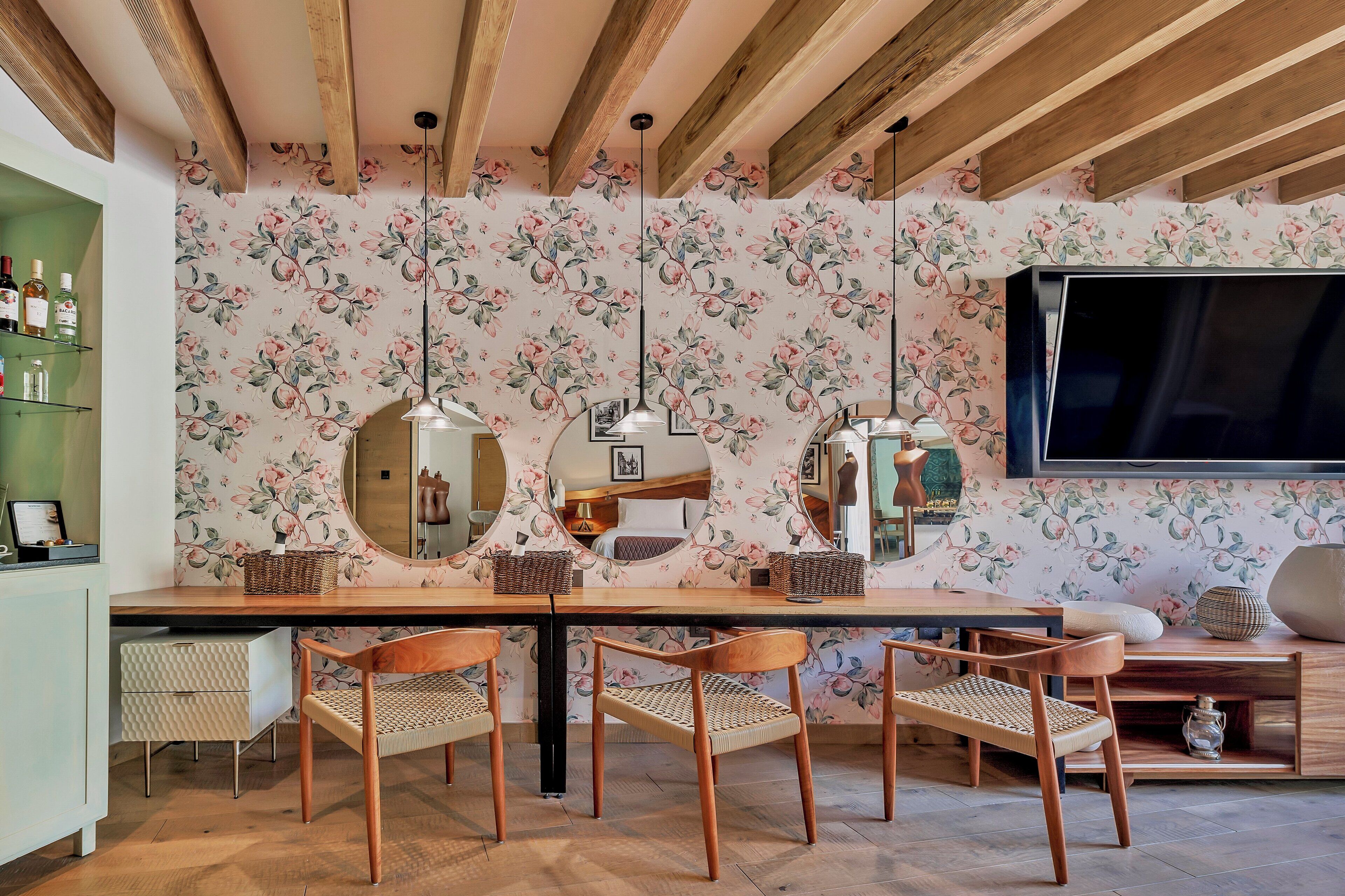 Un comedor con mesa de madera, cuatro sillas y un papel tapiz con motivos florales.