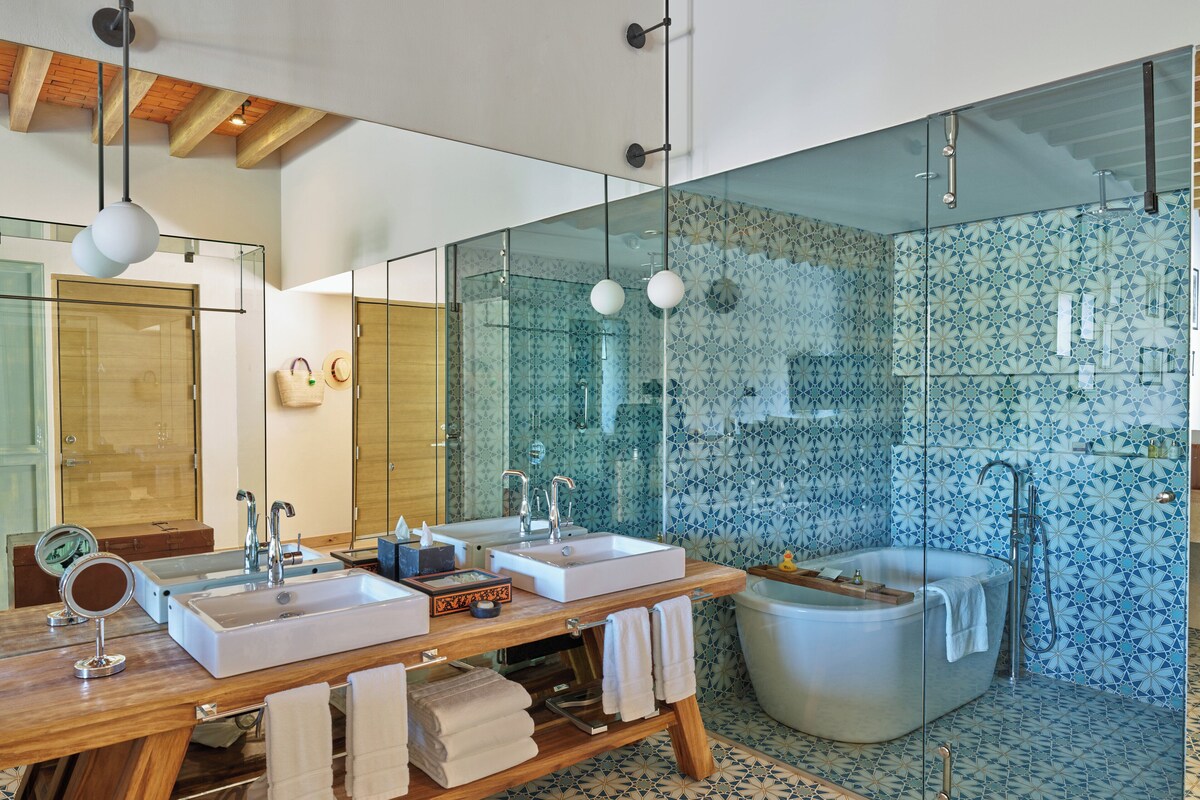 Ein modernes Badezimmer mit zwei Waschbecken, einem großen Spiegel und einer freistehenden Badewanne.