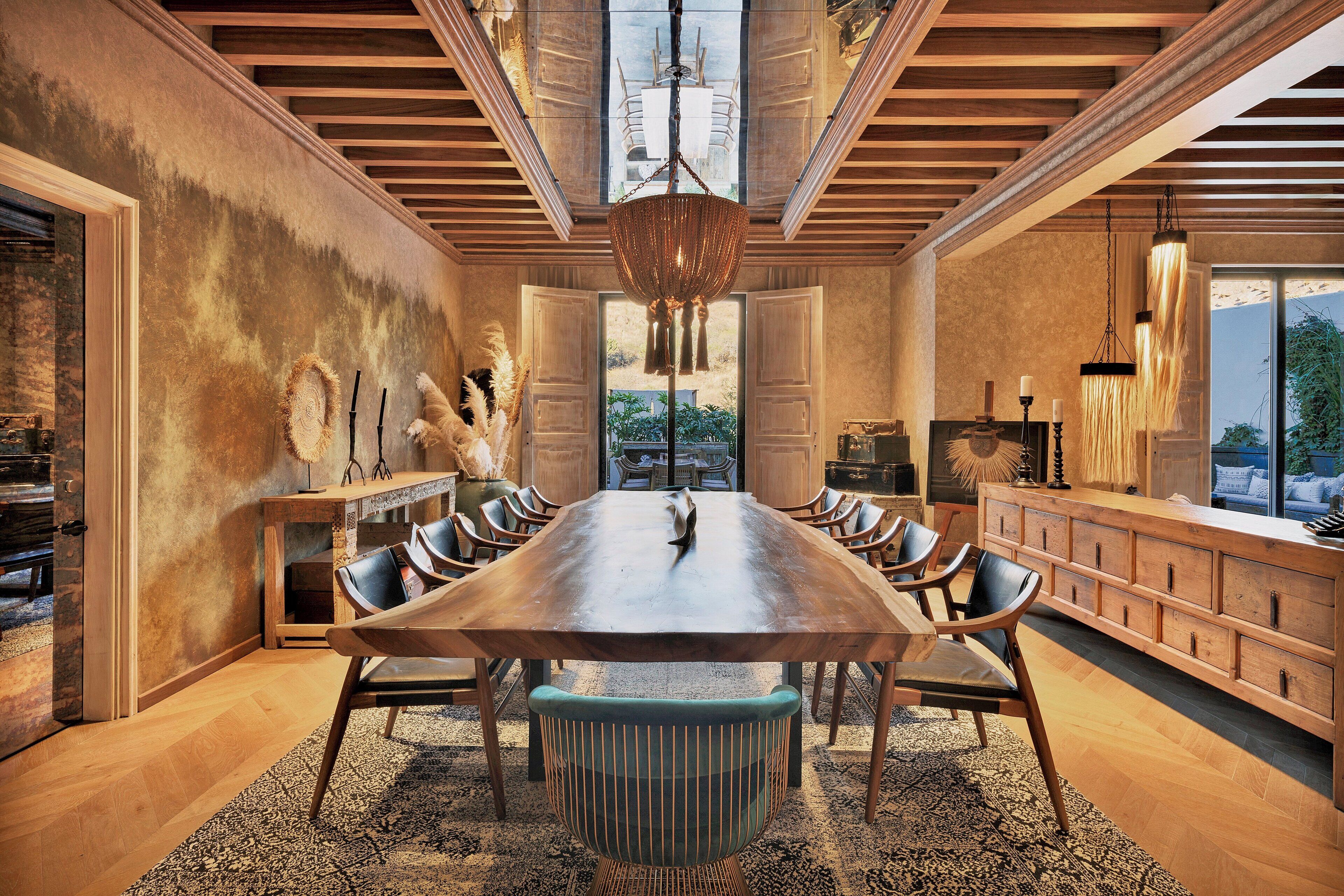 Un'ampia sala da pranzo con un lungo tavolo in legno, numerosi posti a sedere e un'area centrale caratterizzata da sedie dal design originale.