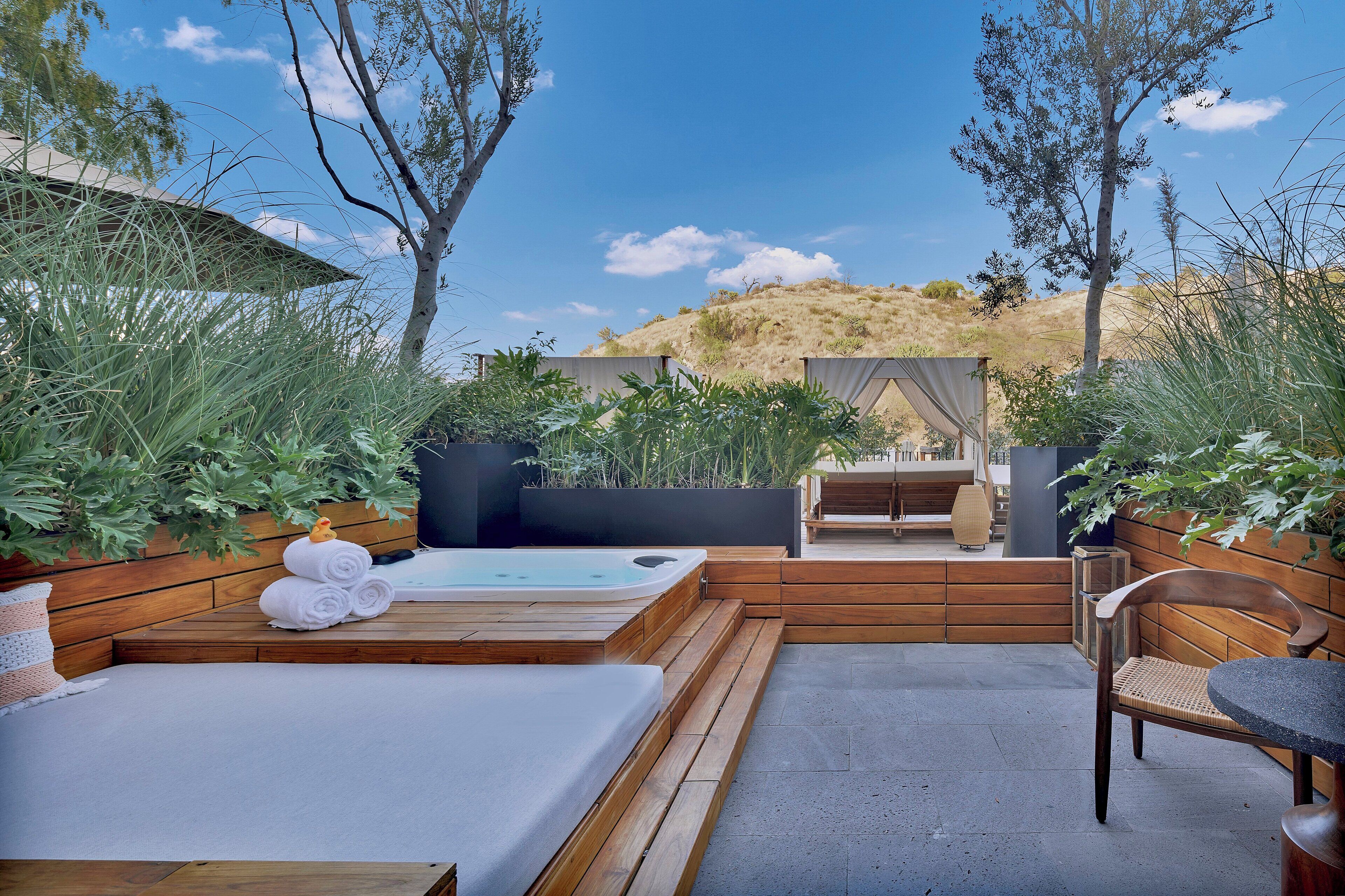 Una terraza de madera con un jacuzzi, un banco y una mesa.