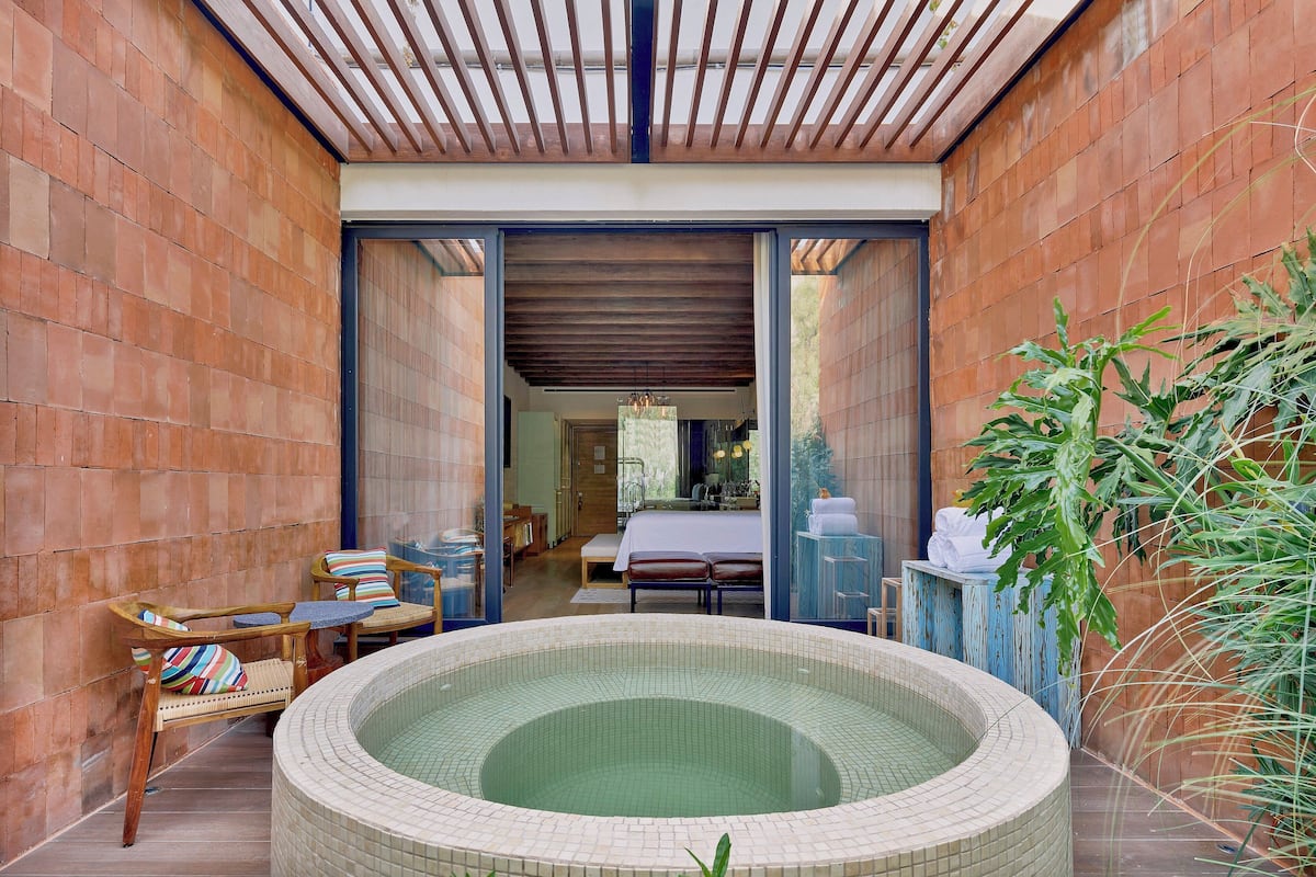 Uma área de spa com hidromassagem, cadeiras de madeira e um banco.