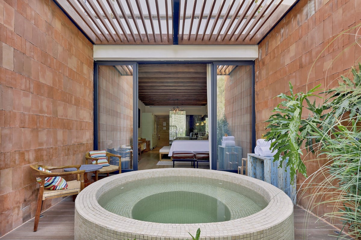 A spa area with a hot tub, wooden chairs, and a bench.