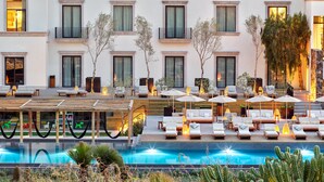 Een hotel met een zwembad, terras en een verzorgde tuin.