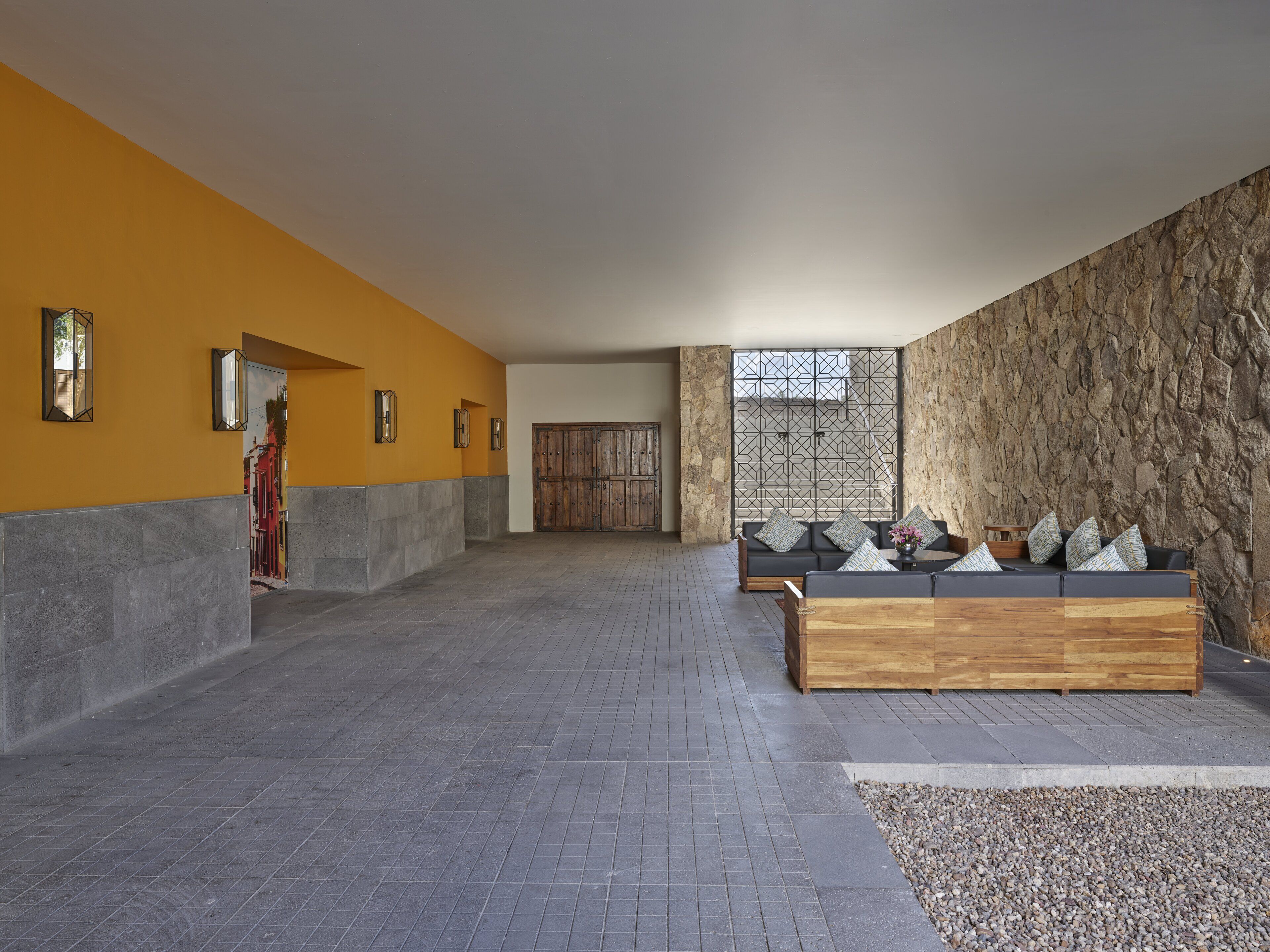 Un vestíbulo amplio con pared de piedra, un banco de madera y un sofá con cojines.