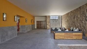 Un vestíbulo amplio con pared de piedra, un banco de madera y un sofá con cojines.
