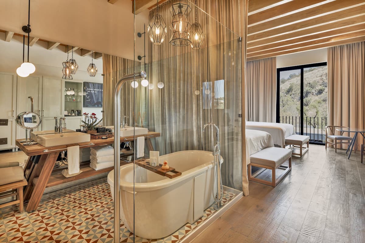 A spacious bathroom with a freestanding bathtub, a large mirror, and a vanity with a wooden countertop.
