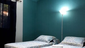 Una habitación con dos camas, paredes color aguamarina y una lámpara en el techo.