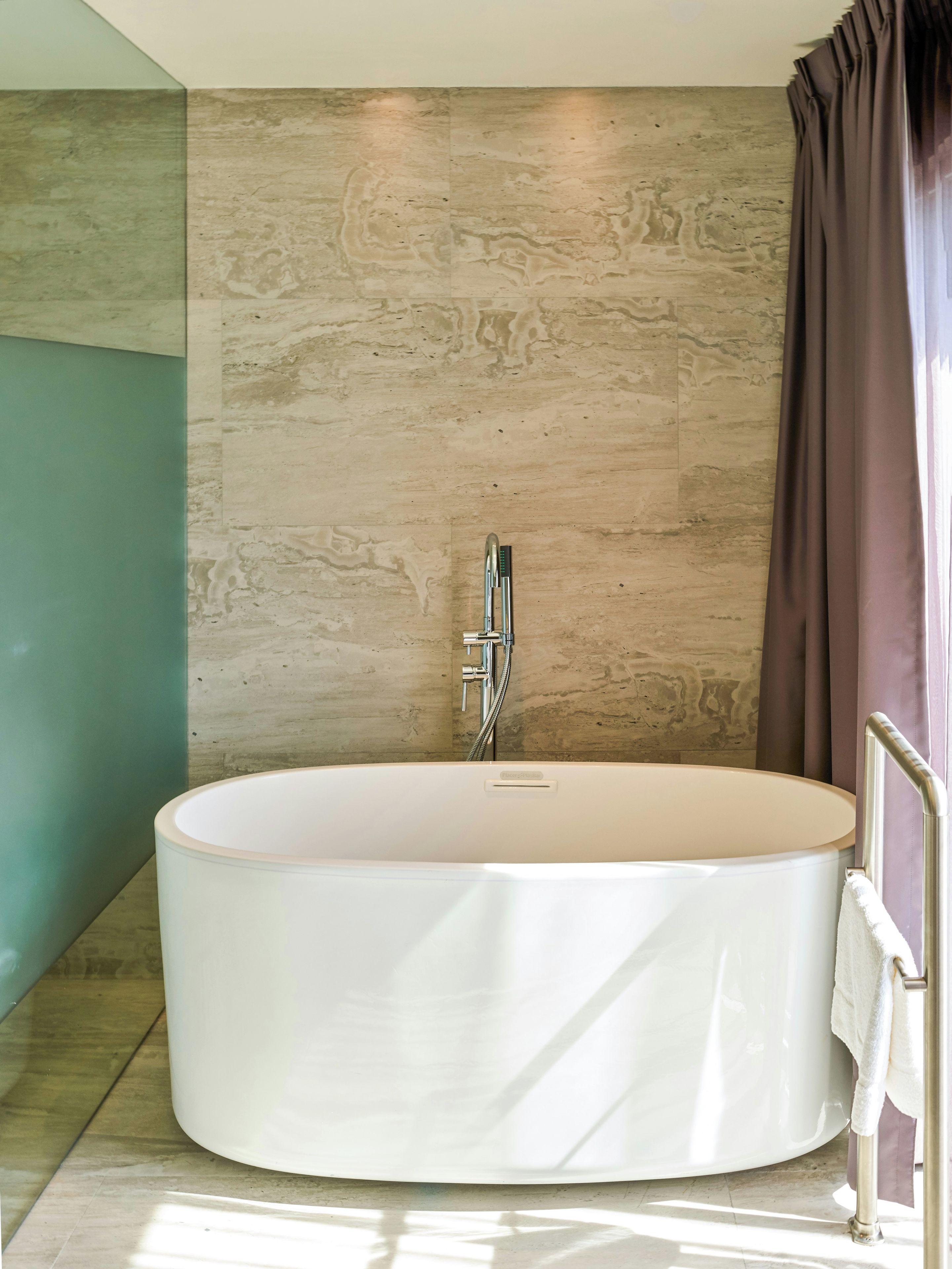 A modern bathroom with a freestanding bathtub, a showerhead, and a towel rack.