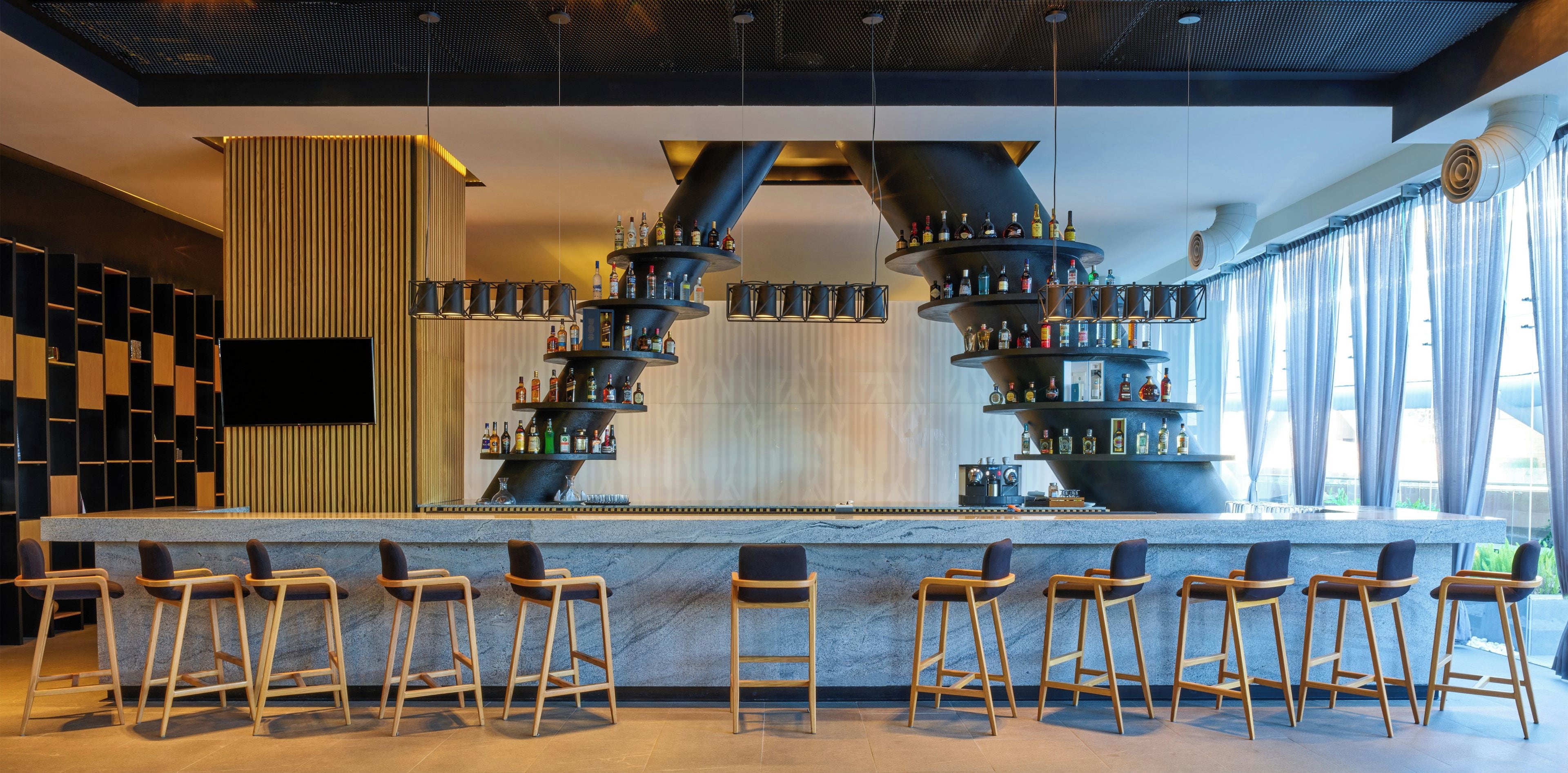 Un espace bar doté de plusieurs distributeurs de boissons alcoolisées, d’un téléviseur à écran plat et de tabourets de bar.