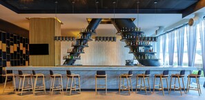 A bar area with multiple liquor dispensers, a flat-screen TV, and bar stools. - Fiesta Americana México Satélite (Tlalnepantla de Baz)