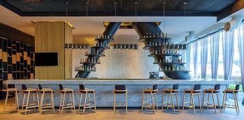 A bar area with multiple liquor dispensers, a flat-screen TV, and bar stools.
