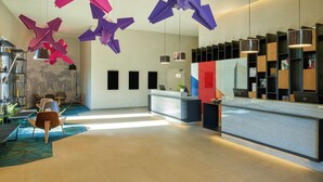 A modern hotel lobby with a reception desk, seating area, and decorative hanging elements. - Fiesta Americana México Satélite (Tlalnepantla de Baz)