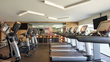 Un gimnasio con varias máquinas de cardio, incluyendo cintas de correr y bicicletas estáticas, dispuestas en filas.