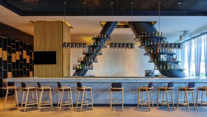 A bar area with a central bar counter, multiple stools, and a unique liquor display.