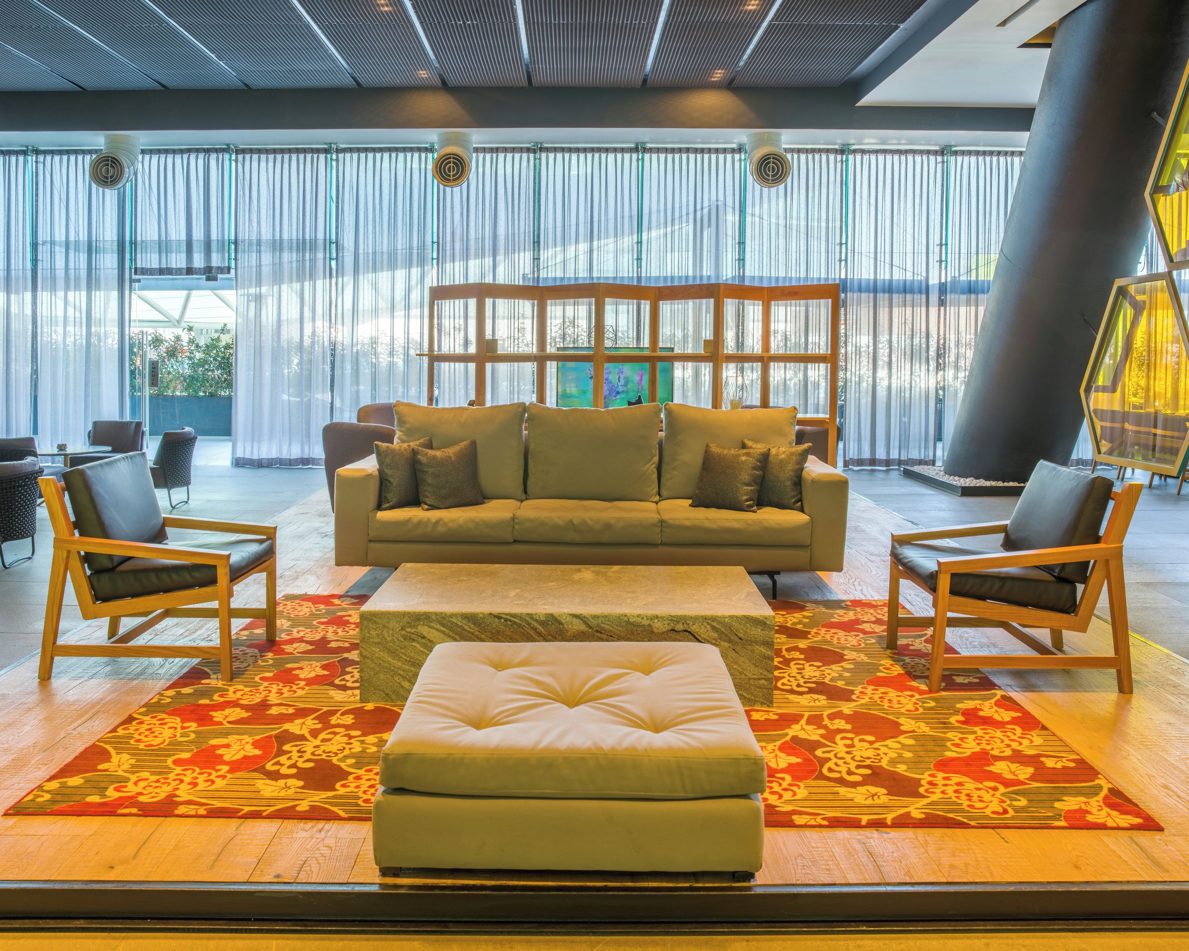 A modern lobby with a sofa set, chairs, and a patterned rug.