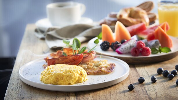 A breakfast plate with scrambled eggs, bacon, and toast, along with a variety of fresh fruits and a glass of orange juice. - Fiesta Americana México Satélite (Tlalnepantla de Baz)